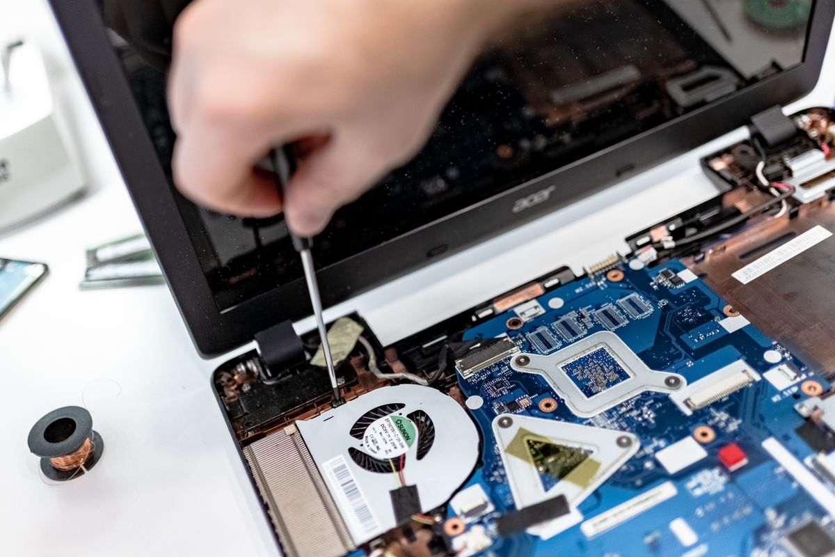 Geopende laptop op de werkbank, het moederbord en de ventilator liggen bloot