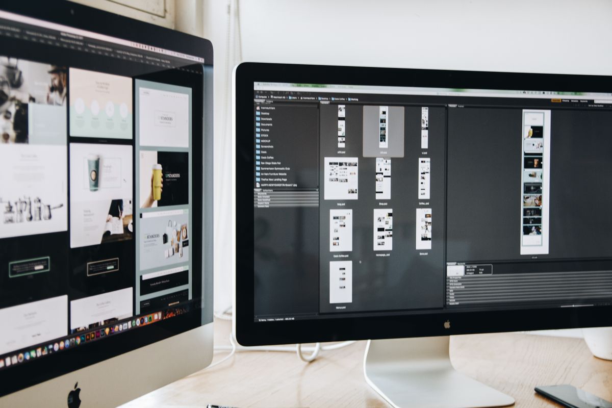Twee beeldschermen op een bureau met een website-ontwerp in bewerking